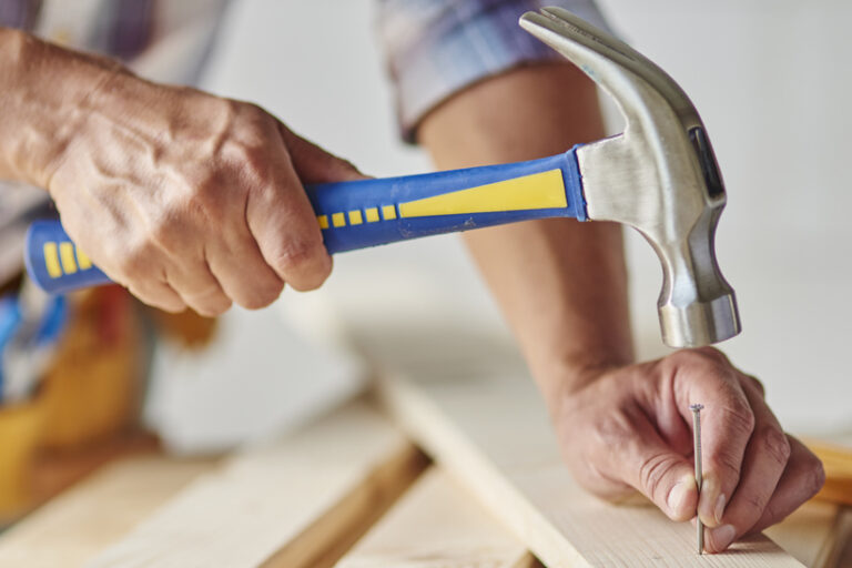 Carpenter with hammer hitting nails